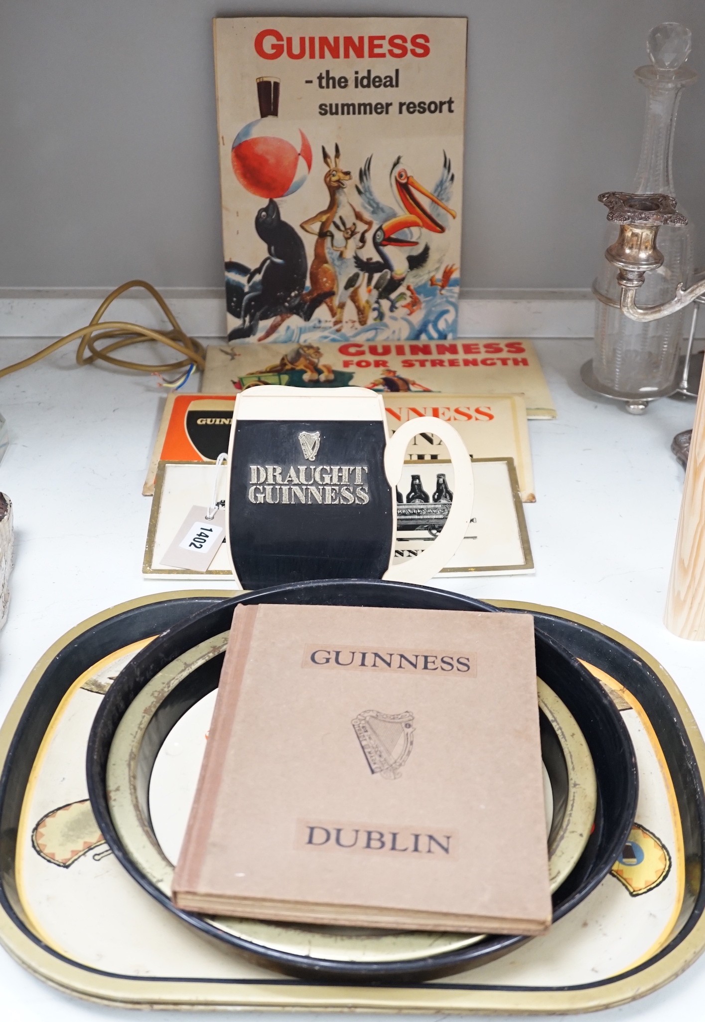 Five Guinness advertising signs, mirror, trays and a book - St. James’s Gate Brewery History and Guide